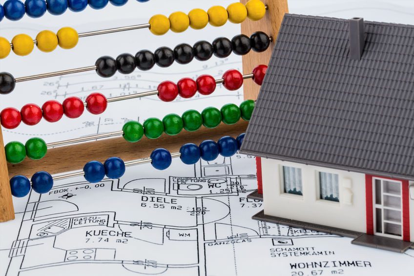 a toy house and abacus of bright coloured beads, sitting on house plan blueprints