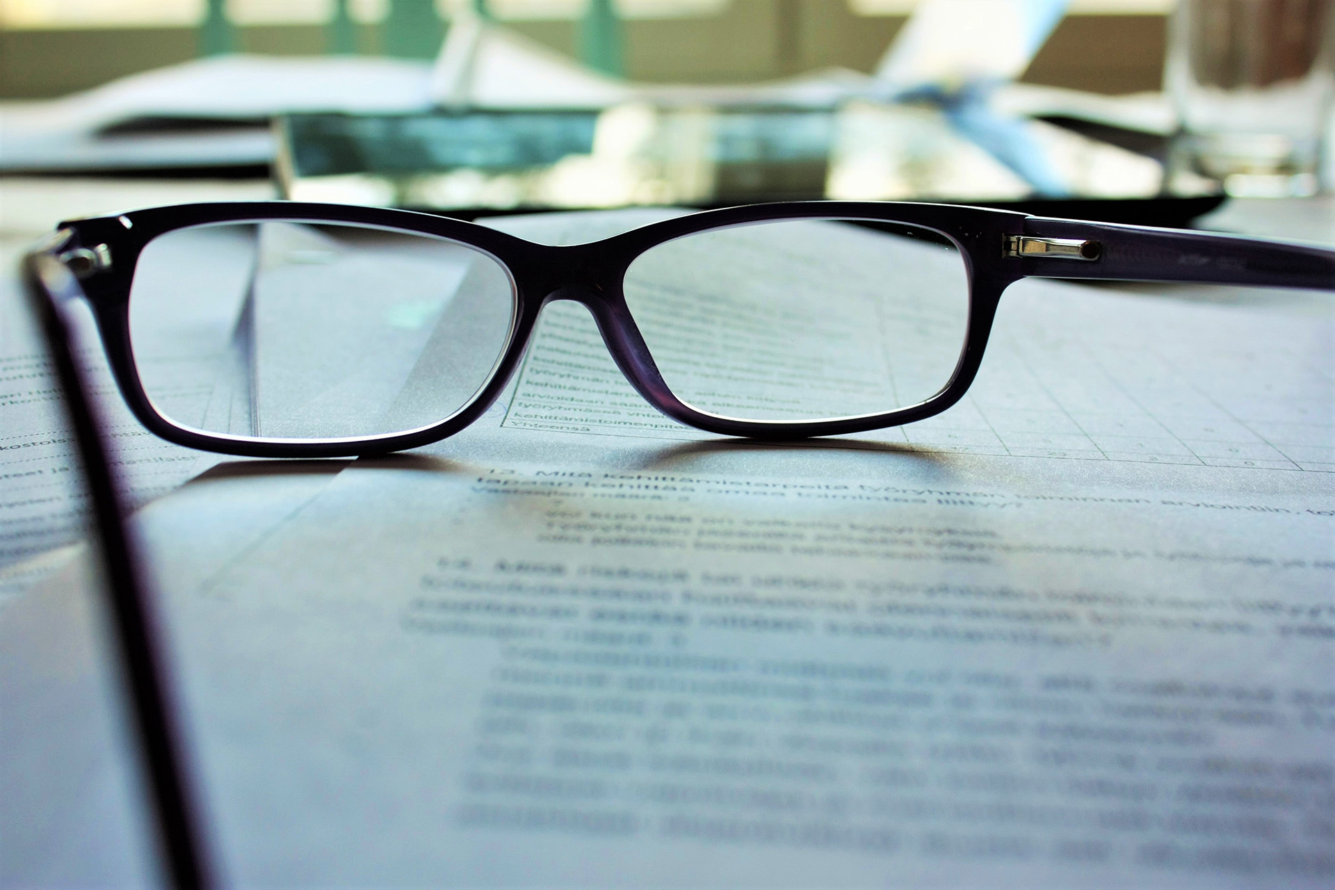 a pair of glasses lying on a contract, highlighting buying a house with subjects
