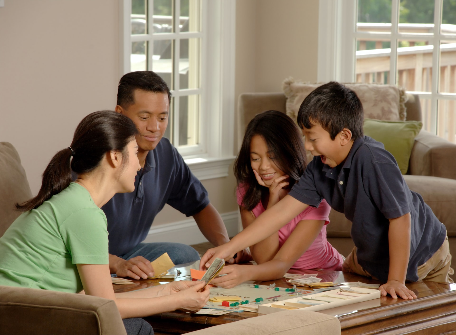 two parents and two kids in a living room of their family home playing board games, highlighting who can co-sign a mortgage