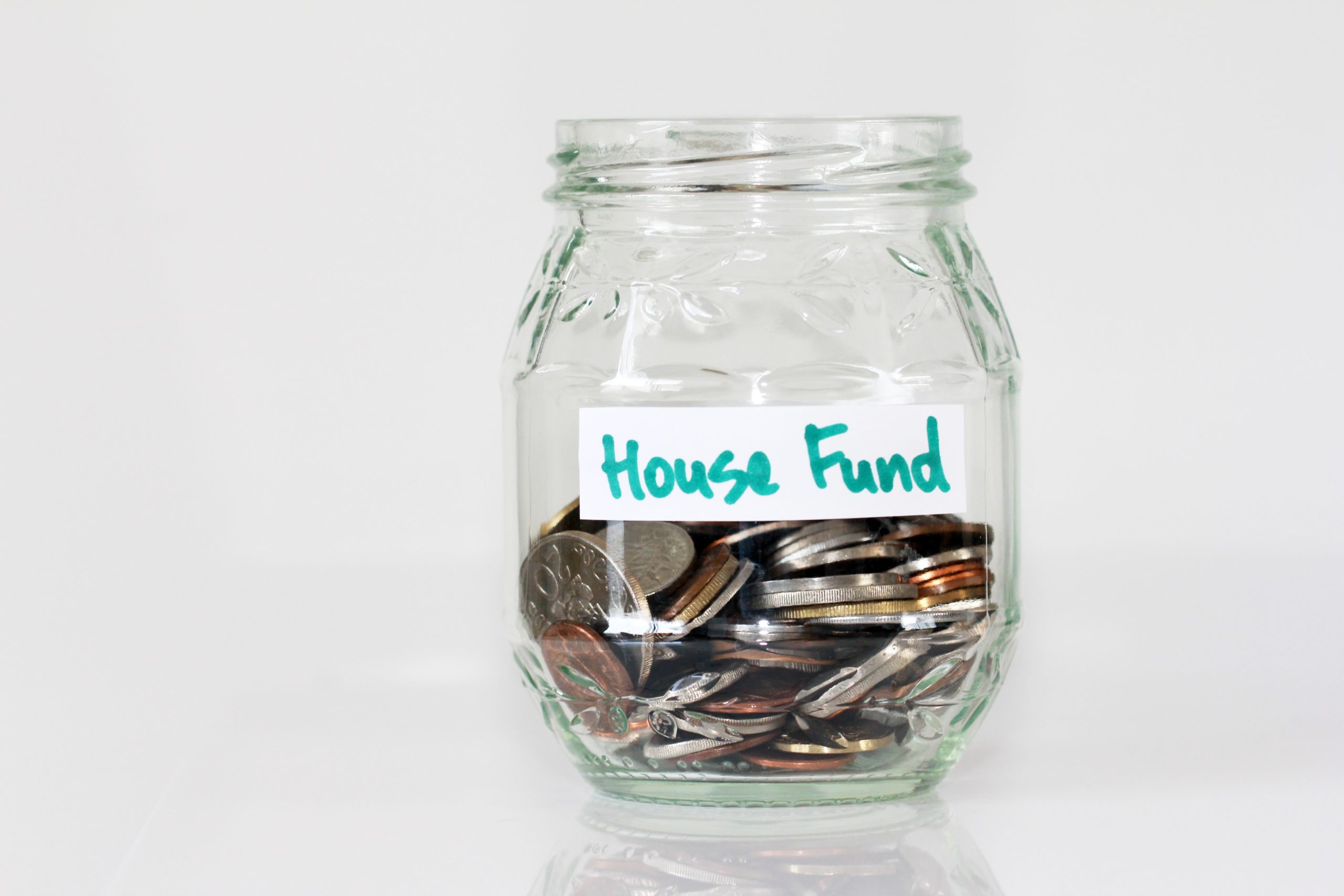 a glass jar with the label House Fund on it, holding coins, in reference to using the home buyers plan and rrsps for a down payment