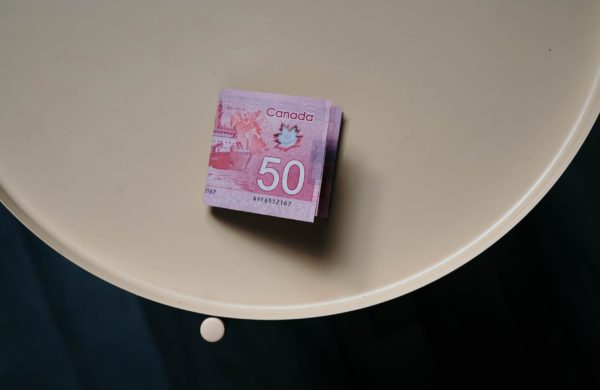 A 50 dollar canadian bill sitting on a beige side table, highlighting the question of whether to lock in your mortgage rate. 