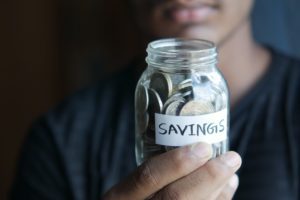 man holding a jar filled with coins with the label savings on it, highlighting saving your your first home with RRSPs.