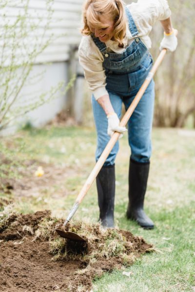 woman raking a new garden, highlighting a spring mortgage checkup